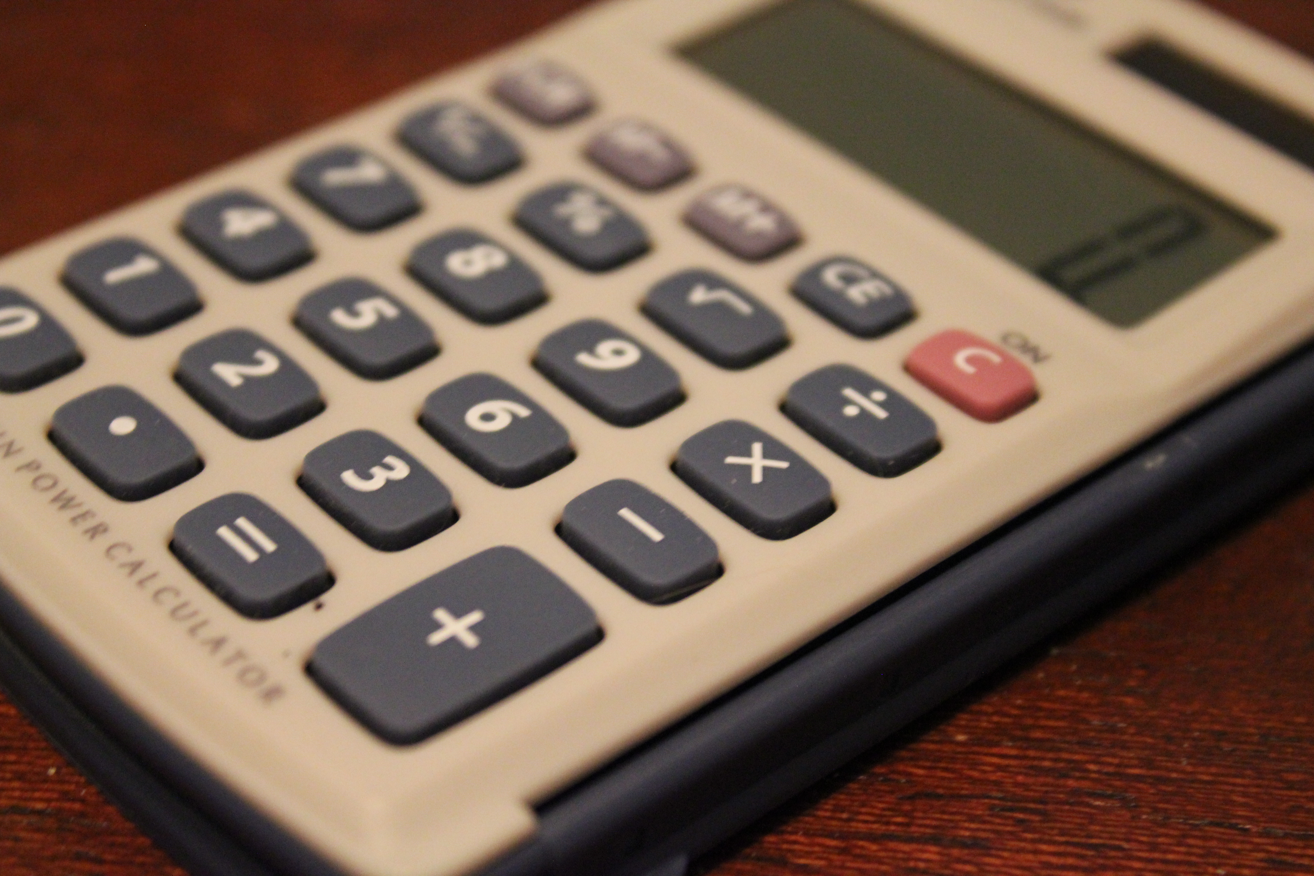 A four-function calculator on a wooden desk