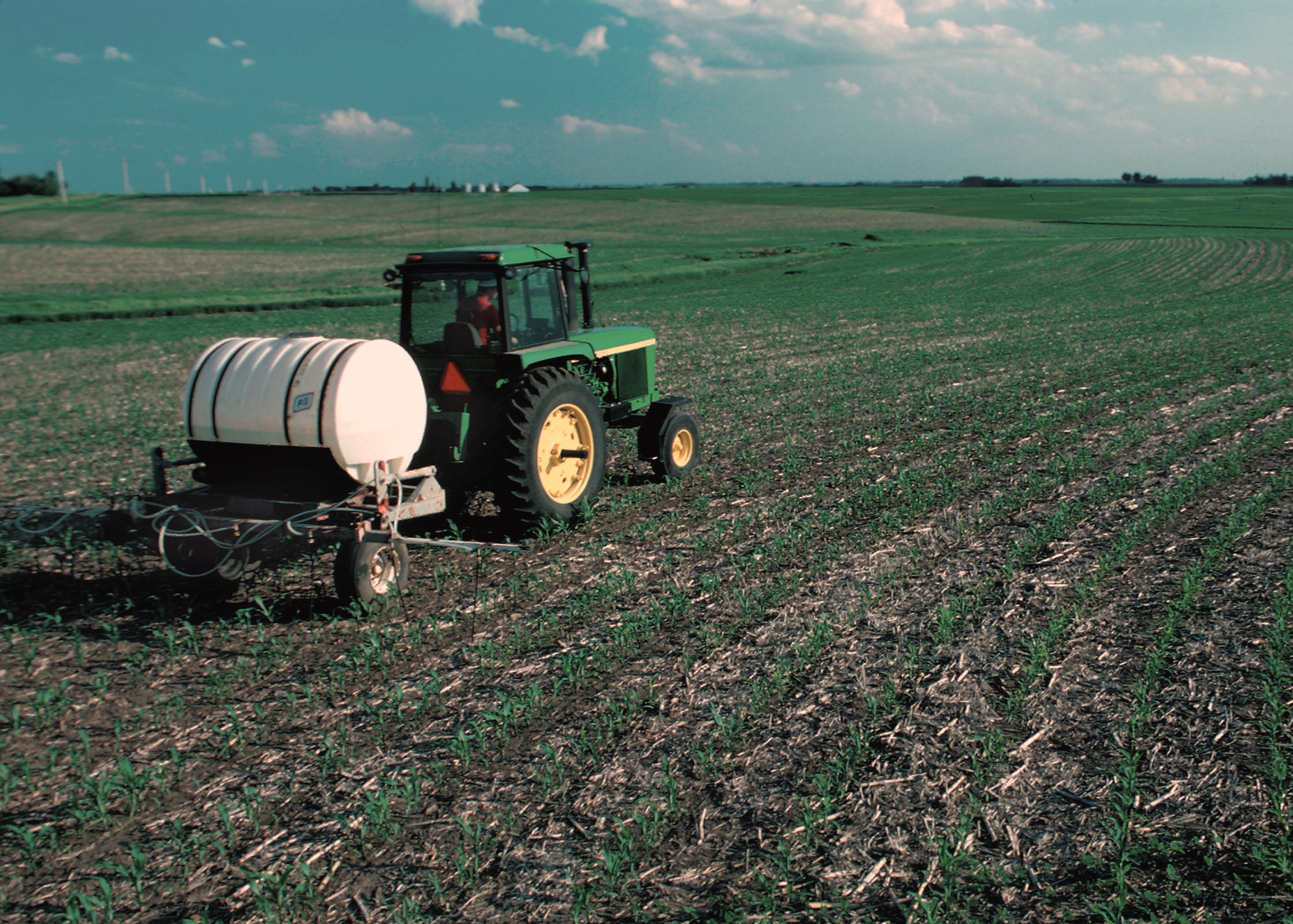 A tractor applying liquid nitrogen fertiliser to young corn in a no-till field in Iowa