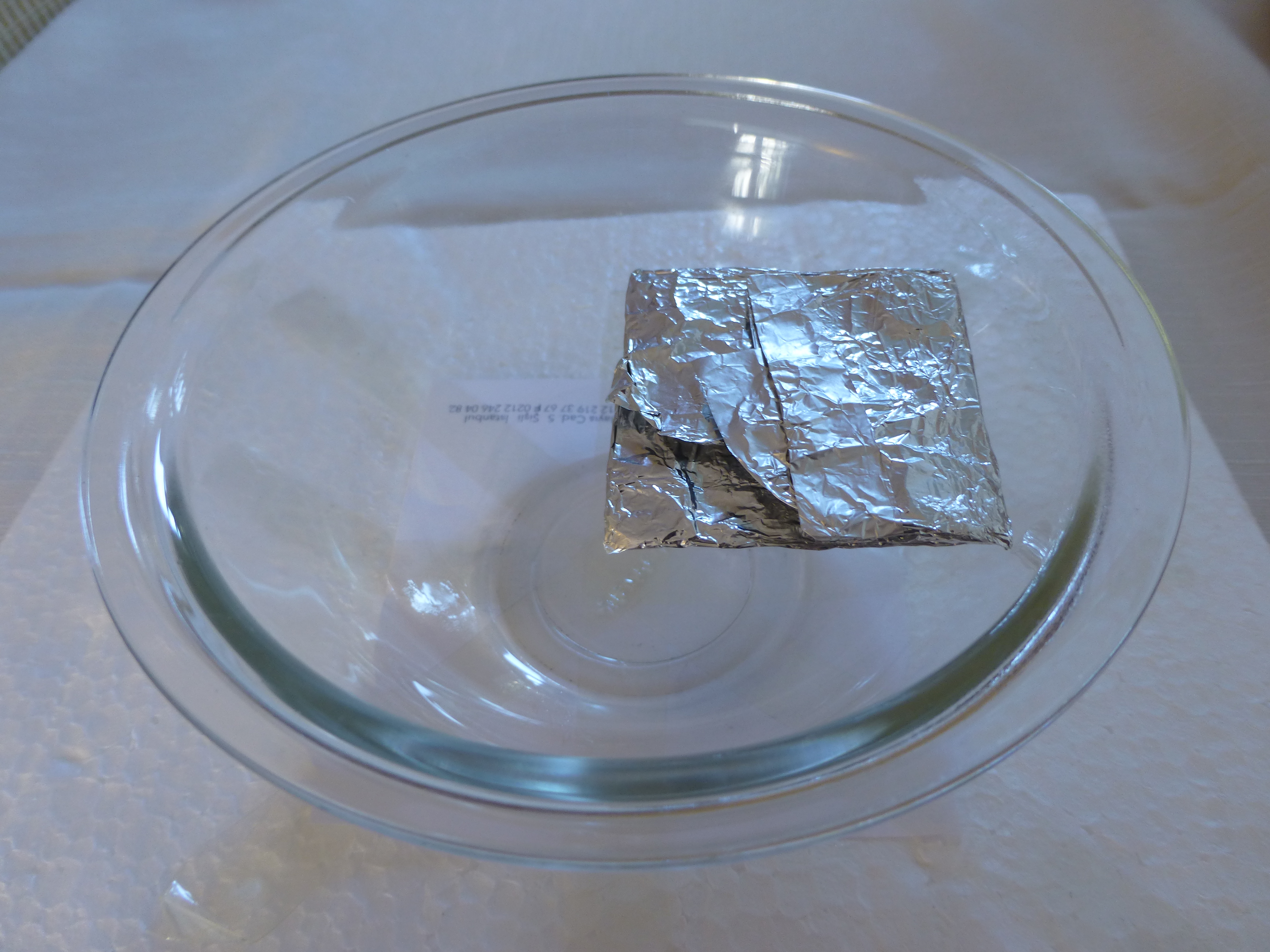 Two foil-wrapped neodymium magnets resting in a glass dish