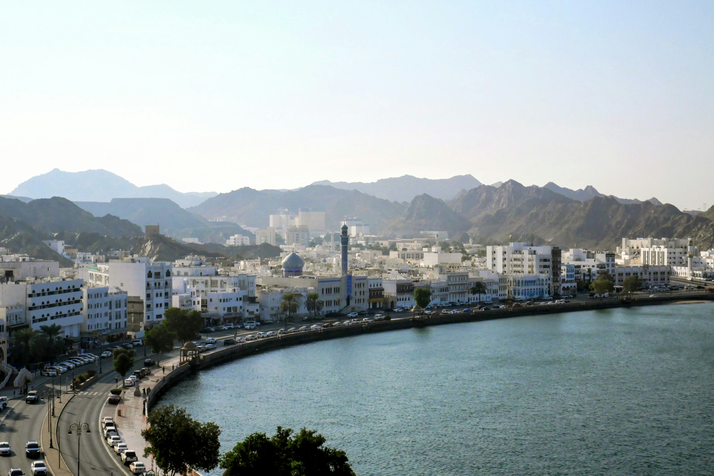 Muttrah Corniche and Muscat’s white waterfront buildings beneath the Hajar Mountains