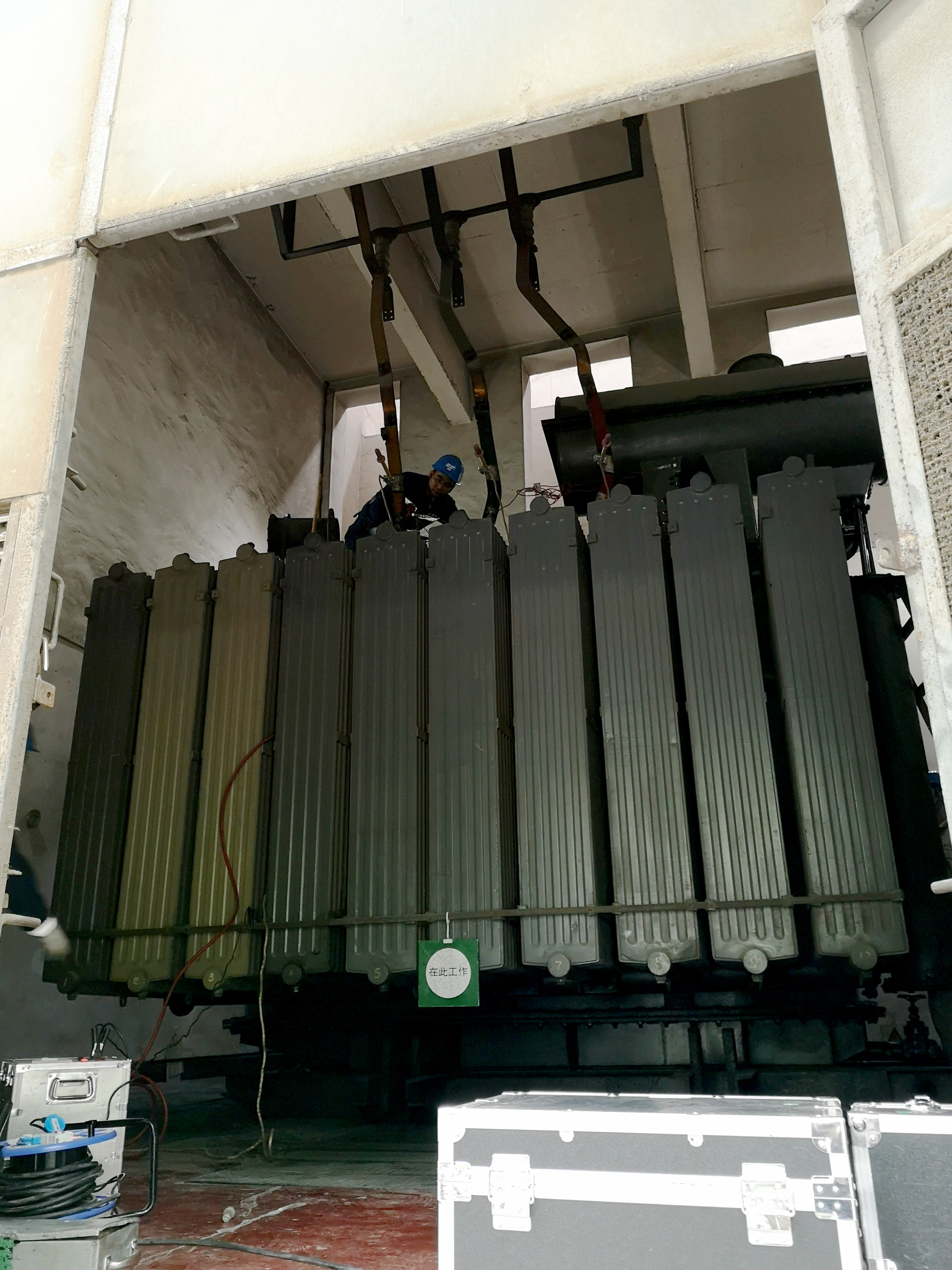 A technician tests a large electrical substation transformer