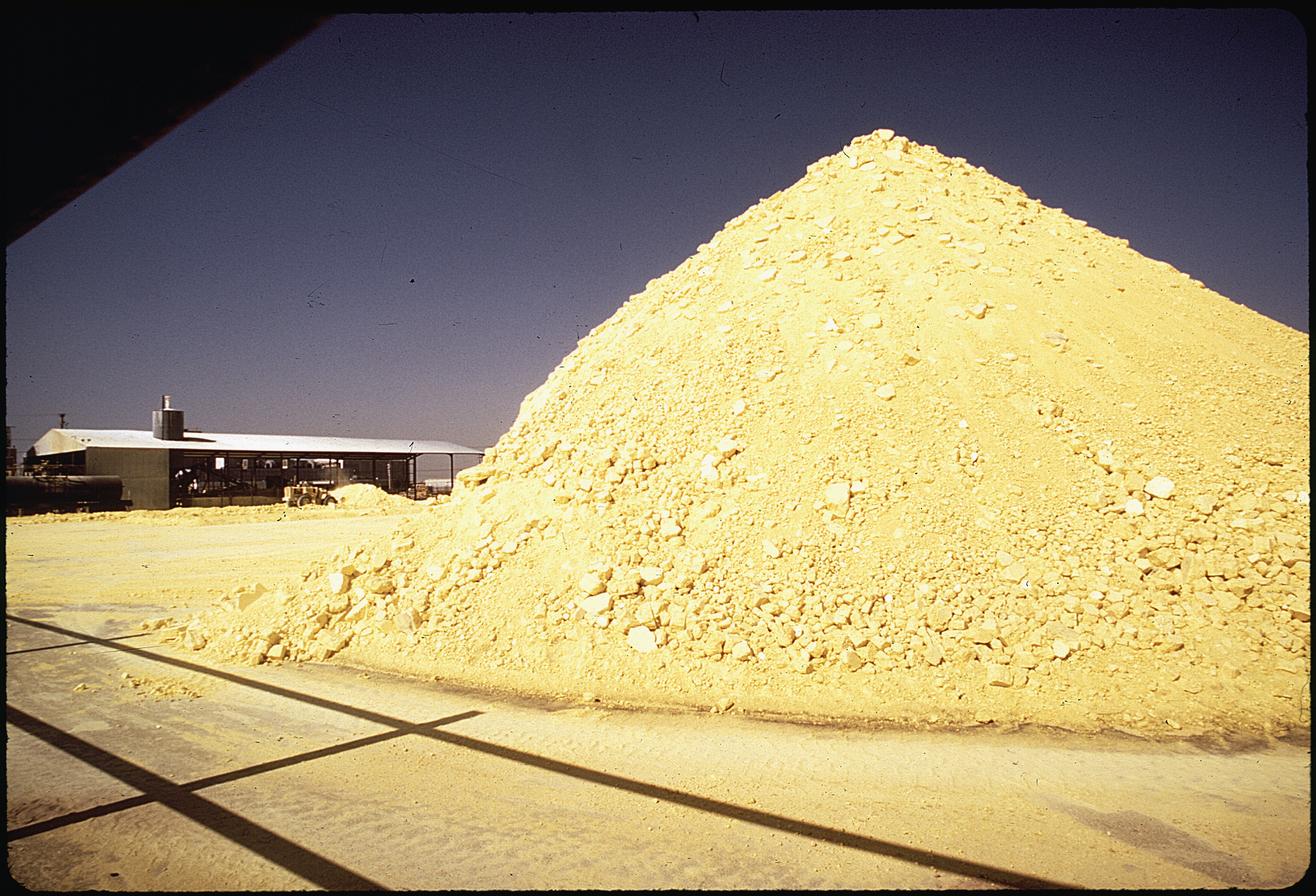 A large yellow pile of recovered sulphur at an industrial processing plant